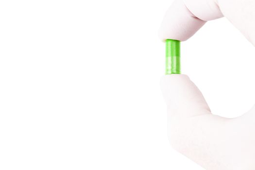 hand in medical glove holding ufo green color organic med capsule isolated on white background closeup.