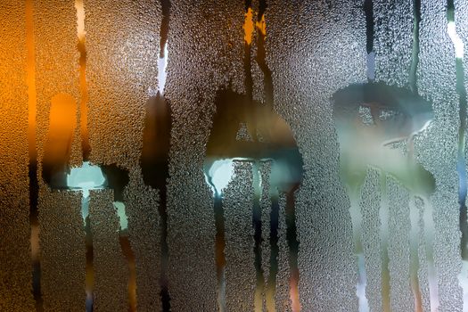 the word liar written on night wet window glass close-up with bokeh background.