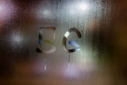 a handwritten word 5G on wet glass with blurred night lights in background.