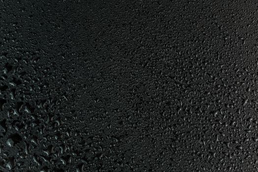 water drops on flat black rubber surface dark macro background