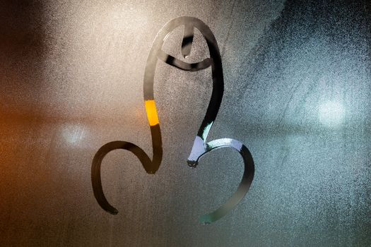 dick symbol drawed by finger on wet glass window at night - close-up with selective focus