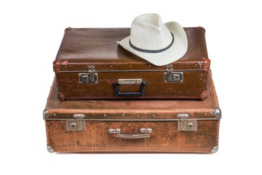 old brown soviet fiber suitcases one on top of other with white summer hat isolated on white background.