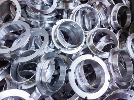 a batch of machined shiny aluminium parts with selective focus.