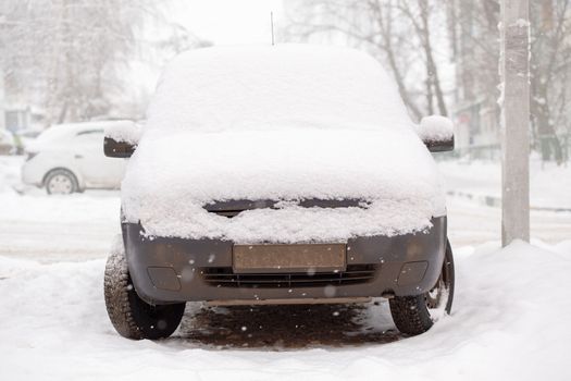 Old dirty car covered by thick snow layer with selective focus.