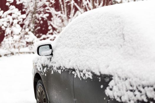 Dirty car covered by thick snow layer with selective focus.