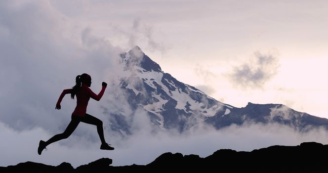 Running woman athlete sport concept. Trail runner exercising in mountain summit background. Female runner on run training outdoors living active fit lifestyle. Silhouette at sunset.