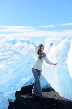 Iceland tourist at Jokulsarlon Iceberg beach walking by icebergs on Ice beach. Breidamerkursandur beach aka Diamond Beach by jokulsarlon glacial lagoon / glacier lake nature landscape. Woman hiking.