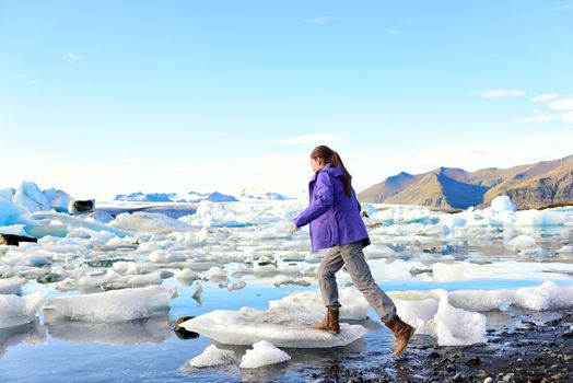 Iceland travel tourist walking on ice looking at view of nature landscape Jokulsarlon glacial lagoon on Iceland. Woman hiking by tourist destination landmark attraction. Vatnajokull National Park.