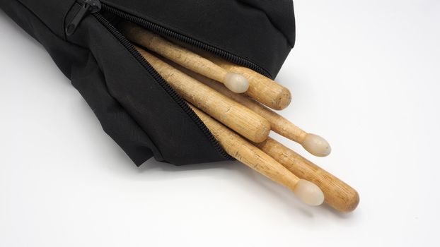 Drum sticks which made from real wood material and black color fabric bags with zip on white background and isolated studio shot.