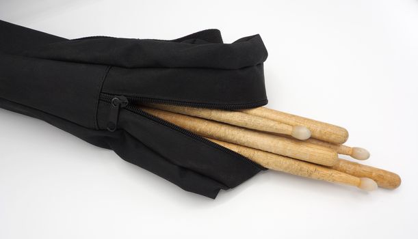 Drum sticks which made from real wood material and black color fabric bags with zip on white background and isolated studio shot.