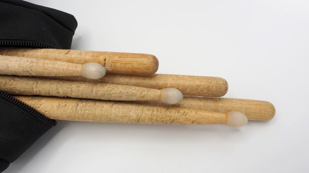 Drum sticks which made from real wood material and black color fabric bags with zip on white background and isolated studio shot.