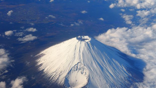 Rare images top view angle of Mt. Fuji mountain and white snow cover on it and light clouds and clear clean blue sky which shoot from airplane.