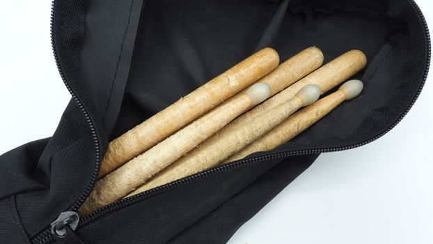 Drum sticks which made from real wood material and black color fabric bags with zip on white background and isolated studio shot.