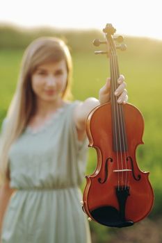 Violin in the hands of a young female violinist in the sunset light. Violin training concept