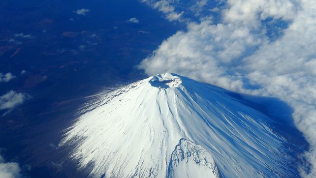 Rare images top view angle of Mt. Fuji mountain and white snow cover on it and light clouds and clear clean blue sky which shoot from airplane.