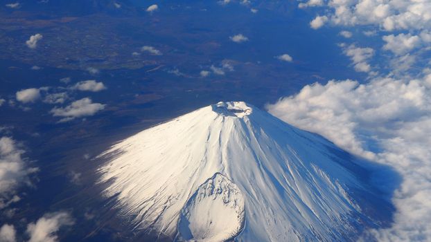 Rare images top view angle of Mt. Fuji mountain and white snow cover on it and light clouds and clear clean blue sky which shoot from airplane.