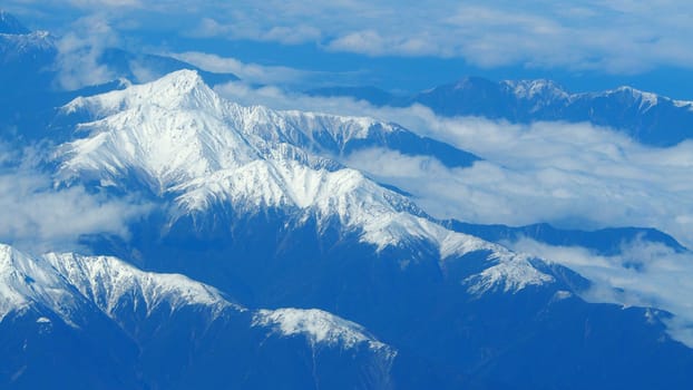 Top view angle images of snow hills around Fuji mountain and white light clouds and blue sky in Tokyo Japan which shoot from airlane.