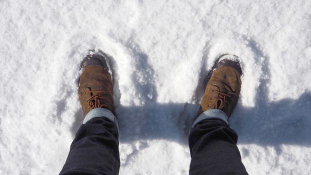 Man brown leather suede boot shoe on the white snow.