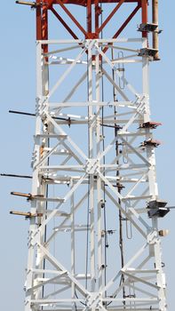 Telecom tower closeup with white color and blue sky.