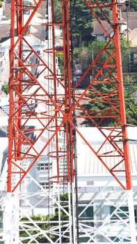 Telecom tower closeup with white and red color and blue sky.