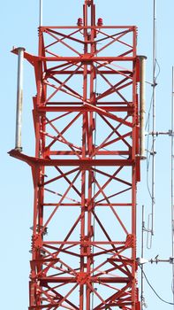 Telecom tower closeup with red color and blue sky.