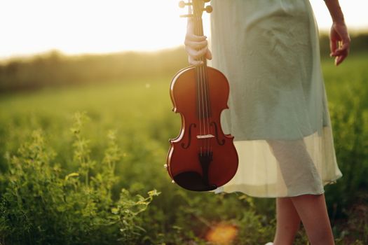 Violin in the hands of a young female violinist in the sunset light. Violin training concept