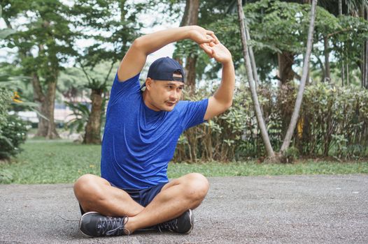 Asian adult men, athletes wearing sportswear, are stretching with yoga postures in the park. Man runner sit and relax after exercise. sportsman fit, healthy body Strong and balanced life