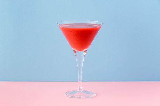 Strawberry smoothie cup on a pink and light blue background. Minimalist image.