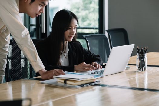 Asian business adviser meeting to analyze and discuss the situation with laptop computer in the meeting room. Investment Consultant.