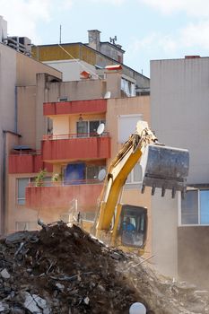 an excavator with a bucket breaks an old residential building close-up