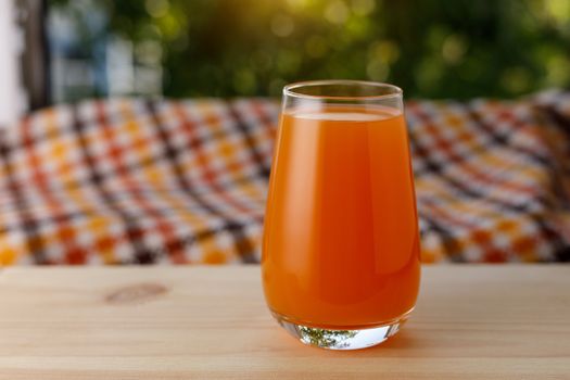 The glass of juice in a garden. The wooden table.