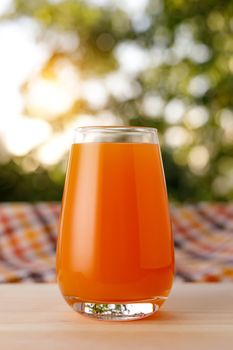 The glass of juice in a garden. The wooden table.