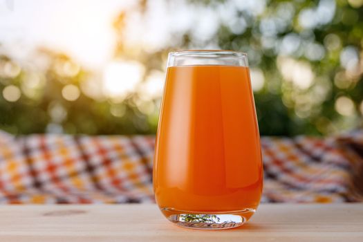 The glass of juice in a garden. The wooden table.