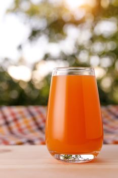 The glass of juice in a garden. The wooden table.