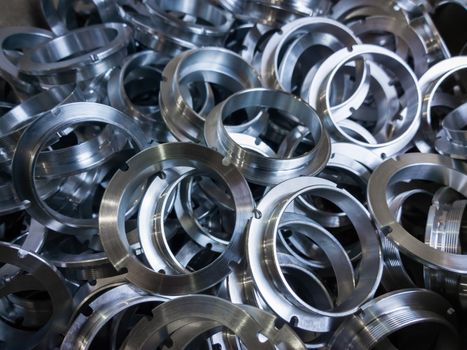 a batch of machined shiny metal parts with selective focus.