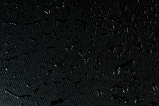 macro background of black flat rubber surface with water drops.