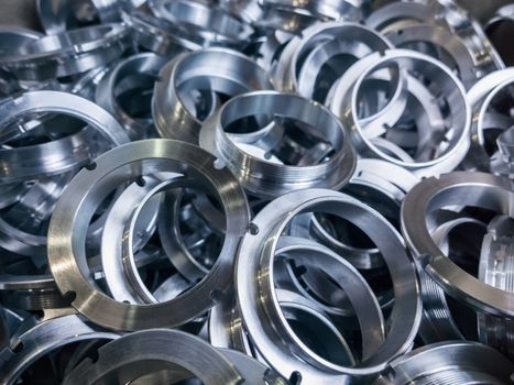 a batch of machined shiny metal parts with selective focus.