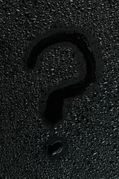 water drops on flat black rubber surface with the handwritten inscription - question mark