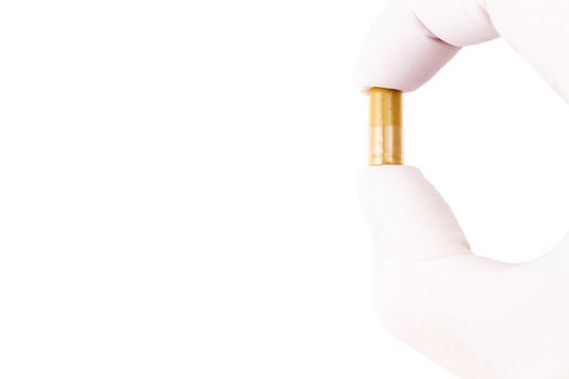 hand in medical glove holding organic med capsule isolated on white background closeup.