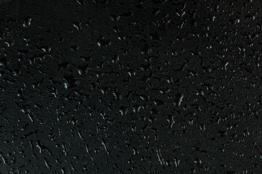 water drops on flat black rubber surface dark macro background