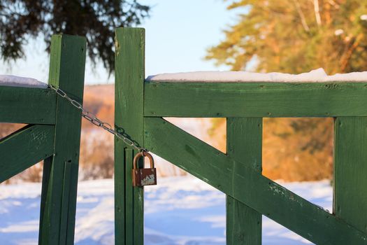 closed wooden gate at winter daylight with chain and padlock