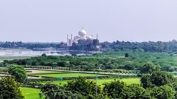 The Taj Mahal from a distance. A different view from far distant of Taj Mahal in the distance with lush greeneries in front. Photography from Agra Fort, South Asia Pac India.