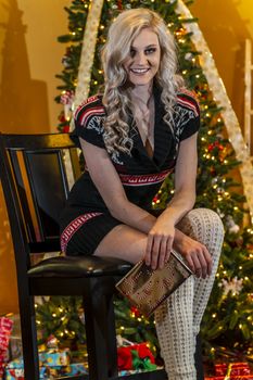 A gorgeous blonde model enjoys the holiday season at home with a Christmas tree and presents