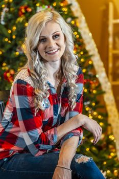 A gorgeous blonde model enjoys the holiday season at home with a Christmas tree and presents