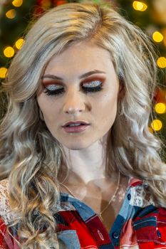 A gorgeous blonde model enjoys the holiday season at home with a Christmas tree and presents