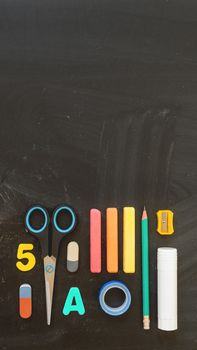 Top view on colorful stationery. Back to school flat lay concept. Vertical blackboard background with copy space. 9-16 ratio for mobile applications.