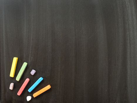 Top view on school blackboard with colorful chalks. Black dirty chalkboard with white chalk traces.. Back to school concept background with copy space.