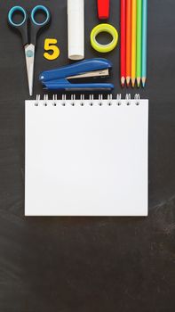 Top view on colorful stationery. Back to school flat lay concept. Vertical blackboard background with copy space. 9-16 ratio for mobile applications.