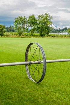 English lawn growing on a farm. Green lawn with irrigation system over the field on cloudy summer day