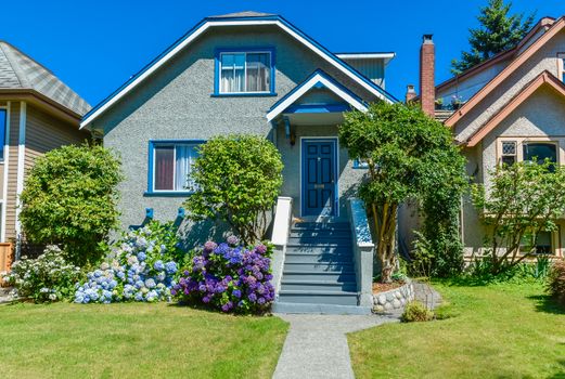 Family house with the pathway over front yard lawn on blue sky background.